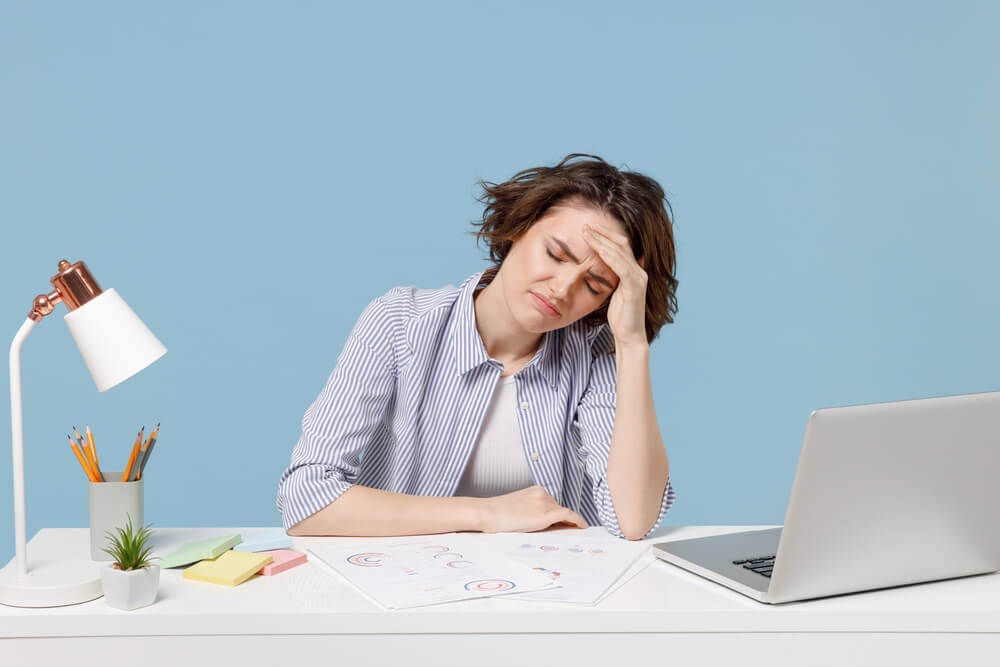 답답한 표정으로 머리에 손을 대고 있는 여성