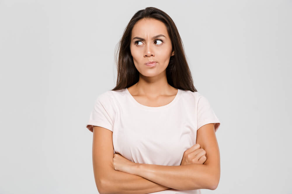 팔짱을 낀 채 뾰루퉁한 표정을 짓고 있는 여자