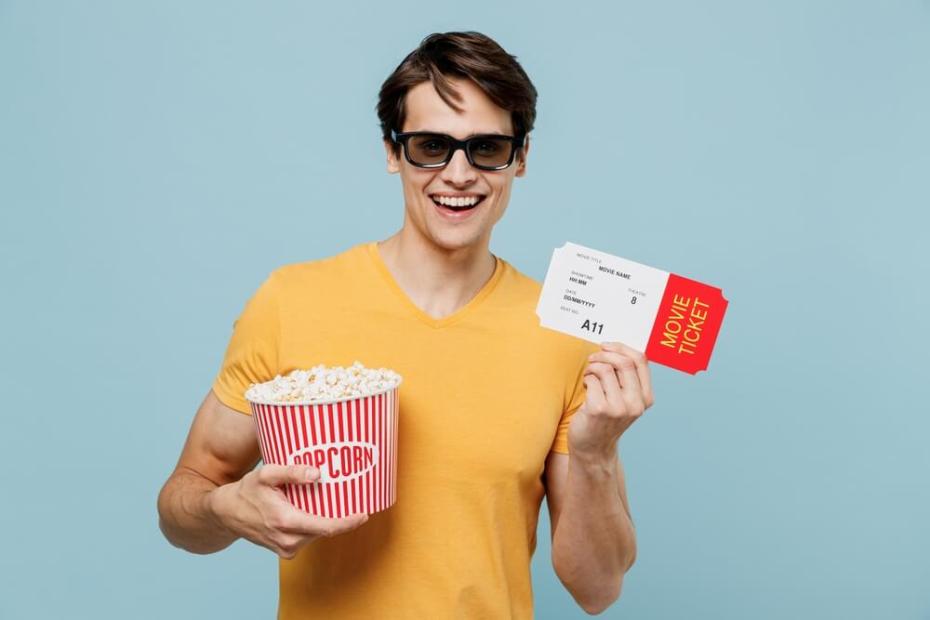 영화관에서 티켓과 팝콘을 들고 있는 남자